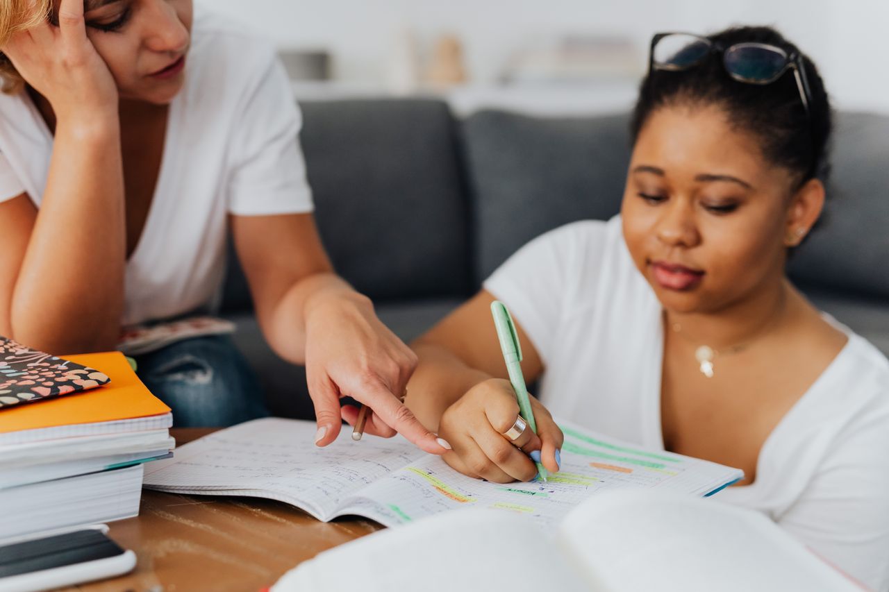 A tutor helping a student work through a maths worksheet at a desk